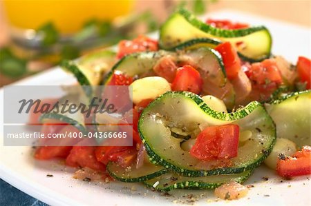 Sauteed zucchini slices, tomato cubes, onion and cooked corn grains with dried herbs and black pepper (Selective Focus, Focus on the front of the zucchini slice and tomato piece in the front)