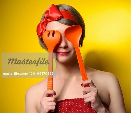 Beautiful pinup style housewife with kitchen utensils
