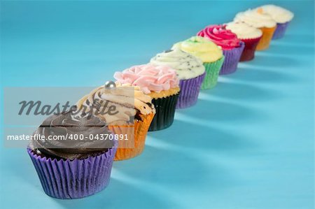 Cupcakes colorful cream muffin arrangement in a row line on turquoise