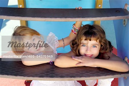 blue eyes little sister girls hide under playground slide stairs smiling