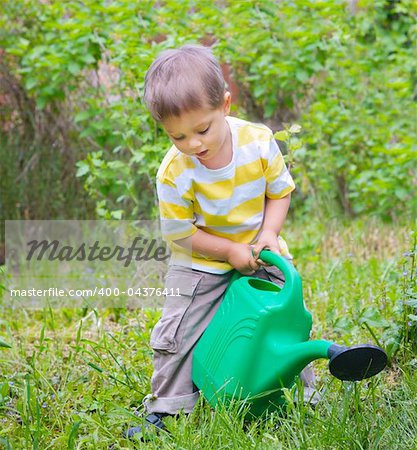 Cute little boy watering the flowers in the garden