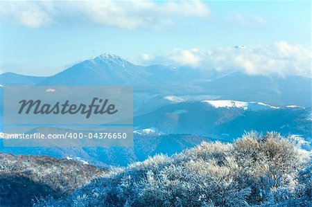 October mountain beech forest edge with first winter snow and last autumn colourful foliage on far mountainside (Carpathian, Ukraine)