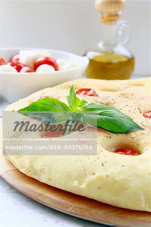 Italian Focaccia bread with tomatoes and basil on a cutting board