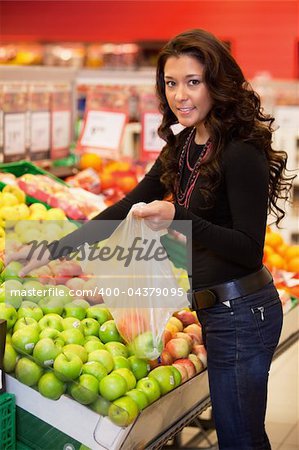 Young woman smiling while buying fruits in the supermarket