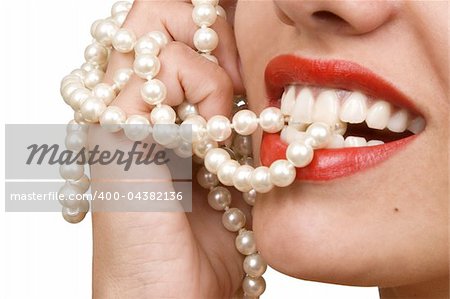 woman smiles showing white teeth, holding a pearly necklace in to the mouth, teeth care concept