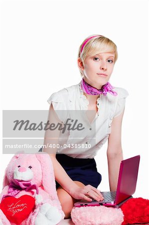 Portrait of beautiful blond girl wearing short skirt and white shoes near pink rabbit working with pink notebook on isolated white background