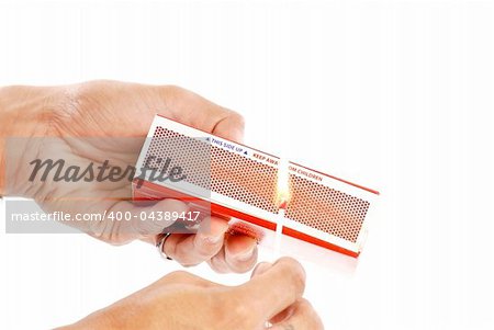 Hand striking match on matchbox against white