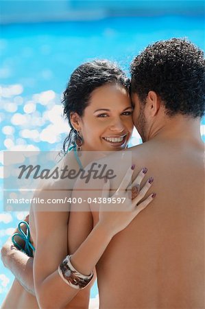 Honeymoon: happy young newlyweds smiling and relaxing near hotel pool. Vertical shape, waist up, copy space