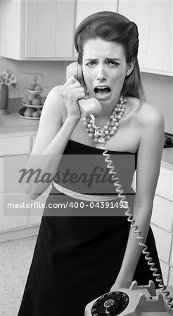 Young Caucasian woman in a kitchen weeps while on the phone