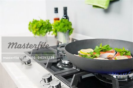 Red fish with mint and lemon prepared in a black skillet in the kitchen