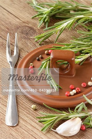 Spices on a ceramic cover, a steel fork and fresh rosemary