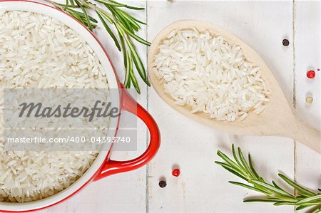 Rice in a red ceramic saucepan and a wooden spoon.