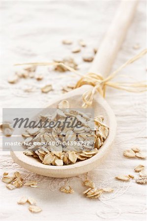 Raw thick rolled oats in a wooden spoon.
