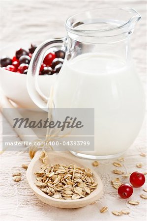 Tasty oat flakes on a spoon, milk and berries.