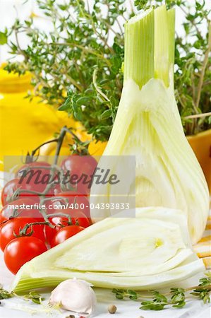 Fennel, tomatoes, olive oil and spices on a white board.