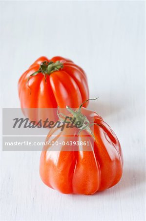 Two heirloom tomatoes on a white wooden board.