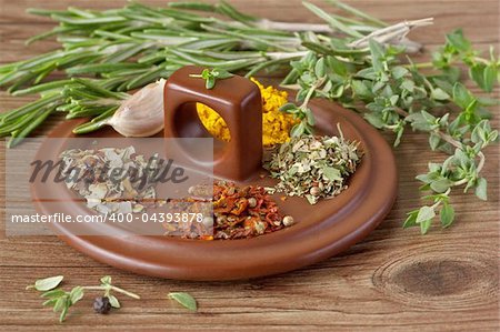 Spices and herbs on a brown ceramic cover.