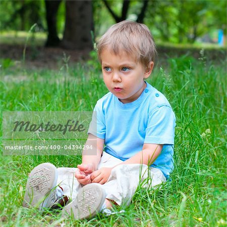 Cute 2 years old boy sitting on the grass in the park