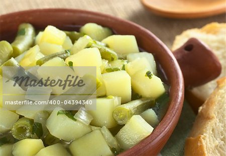 Potato-green-bean hotpot in rustic bowl with baguette on the side (Selective Focus, Focus on the green bean in the middle of the hotpot)