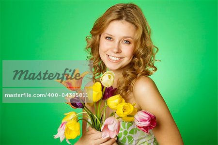 Happy close-up on a green background happy young woman hugging a bouquet of colorful tulips