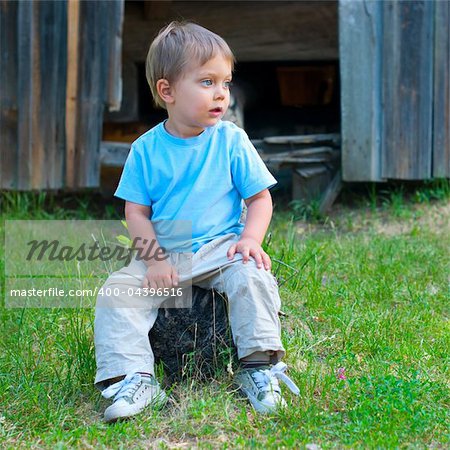 Cute 2 years old boy sitting on the the bench in the park