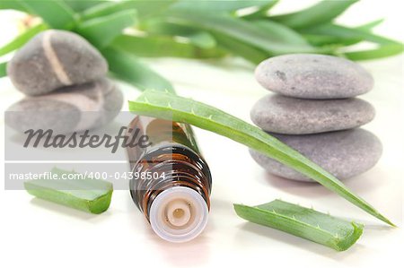 Aloe Vera drops with bottles, Aloe Vera and pebbles on white background
