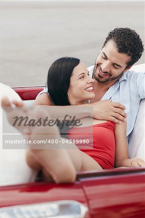 boyfriend and girlfriend lying inside vintage convertible car and hugging. Vertical shape, front view, copy space