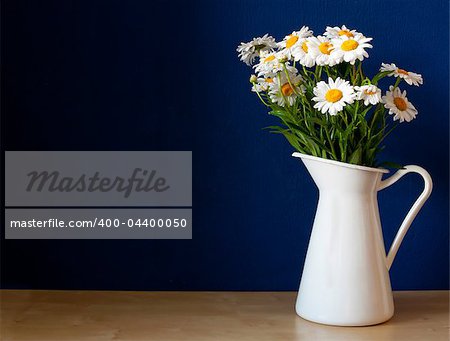 Fresh Oxeye Daisies on table in white Pitcher in interior