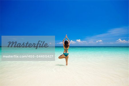 Woman doing yoga (tree pose) on the beach