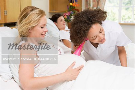 Nurse checking pregnant woman's belly and smiling