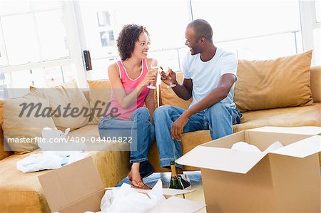 Couple toasting champagne by boxes in new home smiling