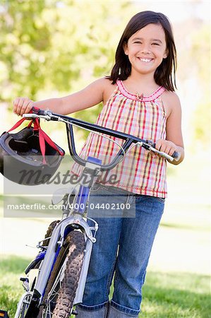 Young girl with bicycle outdoors smiling