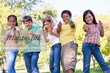 Five young friends with water guns outdoors smiling