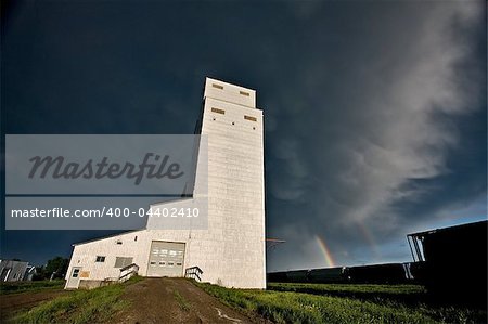 Prairie Grain Elevator in Saskatchewan Canada with storm clouds and rainbow