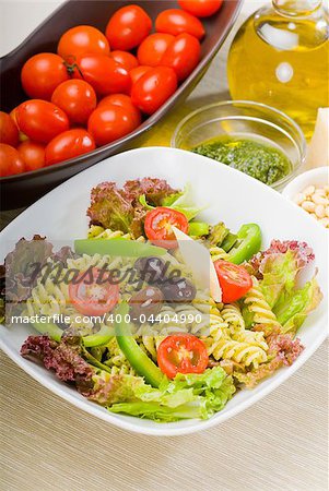 fresh healthy homemade italian fusilli pasta salad with parmesan cheese,pachino cherry tomatoes, black olives and mix vegetables ,dressed with extra-virgin olive oil and pesto sauce