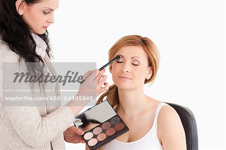Young woman having her make up done by a make up artist in a studio