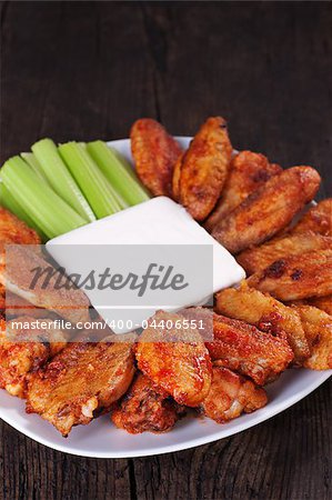 Buffalo chicken wings on plate with blue cheese sauce and celery.