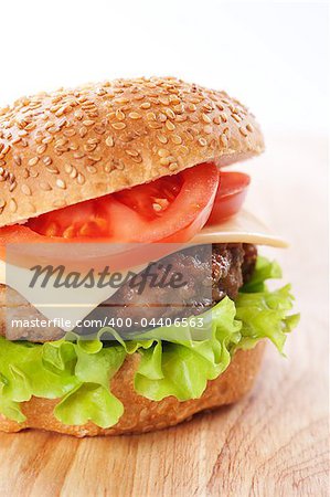 Cheeseburger with tomatoes and lettuce on a wooden table