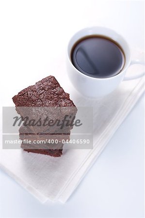 Chocolate brownies on white napkin and cup of coffee