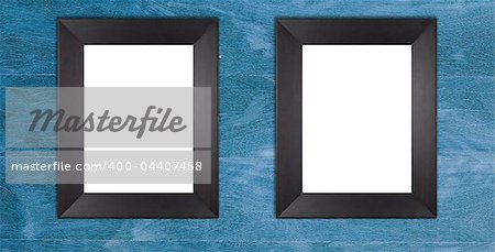 Two blank wooden black frames on blue painted wooden wall.