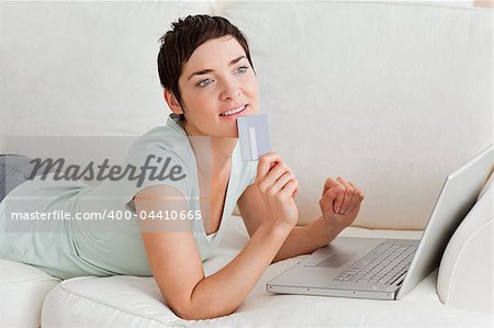 Pensive woman buying online in her living room