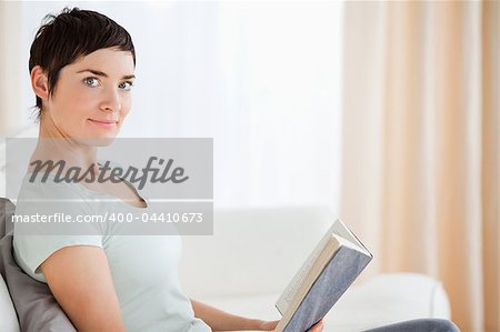 Short-haired woman holding a book while lokking at the camera