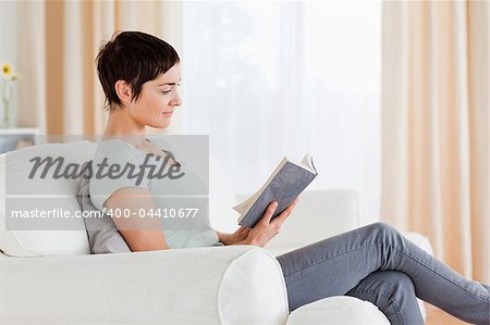 Short-haired brunette reading a book in her living room