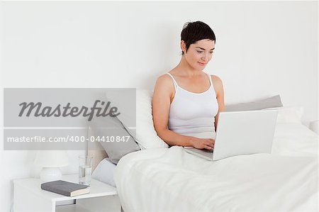Beautiful woman using a laptop in her bedroom