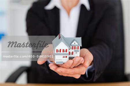 Feminine hands holding a miniature house in an office