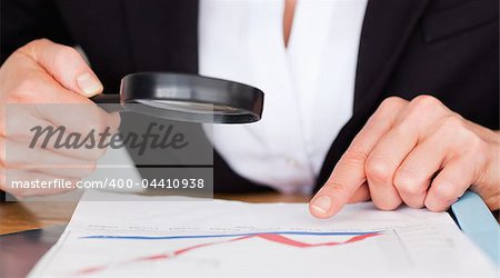 Female hands holding a magnifying glass above a chart