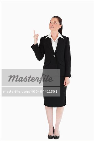 Attractive female in suit pointing at a copy space while standing against a white background