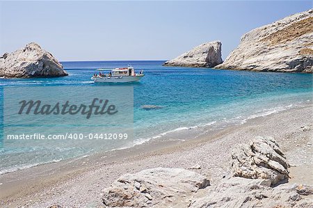 A boat transferring tourists arrives at the remote Katergo beach, Folegandros island, Greece