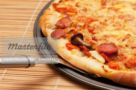 A slice of pizza is lifted from the pan with a spatula