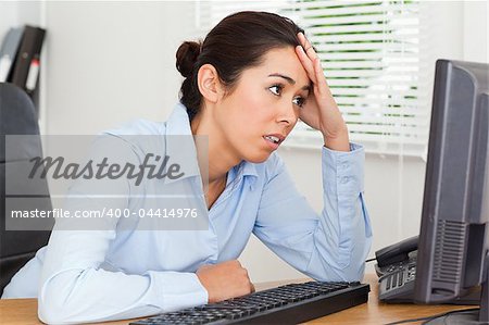 Beautiful upset woman looking at a computer screen while sitting at the office